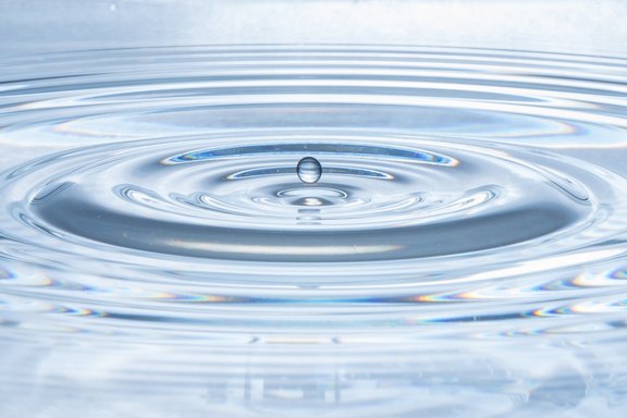 Wassertropfen fallen ins Wasser und bilden Kreise auf der Oberfläche.