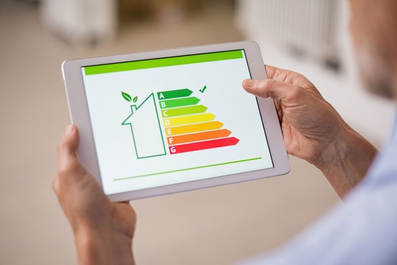 Hand, die ein digitales Tablet hält und sich die Effizienzbewertung des Hauses ansieht. Detail der Hauseffizienzbewertung auf dem digitalen Tablet-Bildschirm. Konzept des ökologischen und bioenergetischen Hauses.
