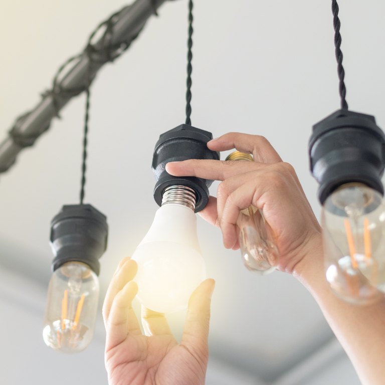 LED-Licht Energiesparkonzept. Mann, der Kompaktleuchtstofflampen (CFL) durch neue Glühbirnen ersetzt.