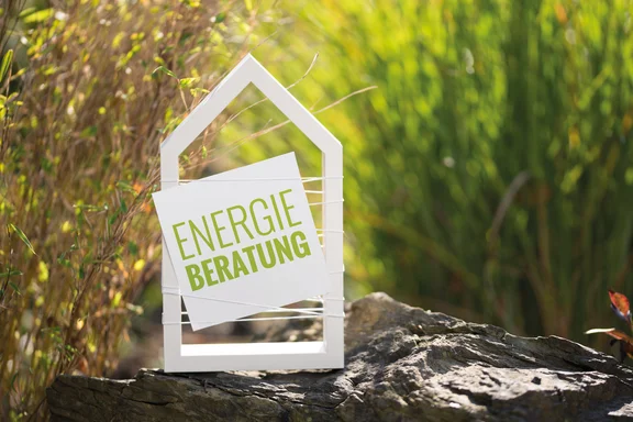 Weißes Haus vor natürlichen Hintergrund mit Schild Energieberatung