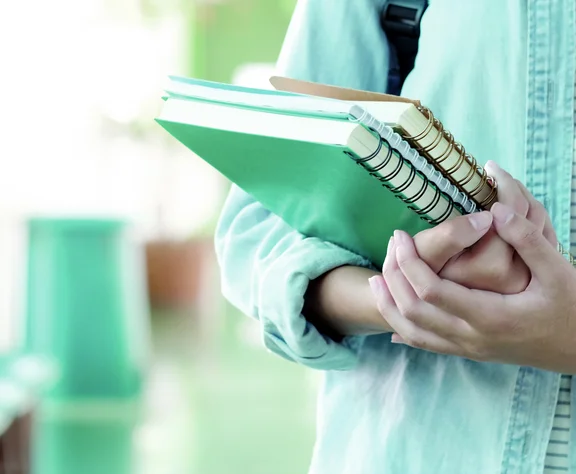 Studentin, die Bücher hält und Schultasche trägt